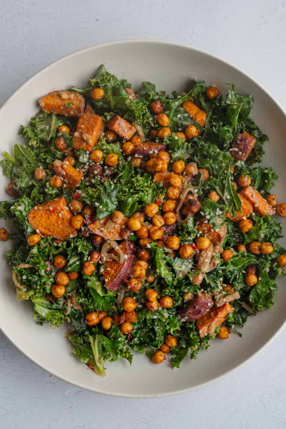 Kale topped with roasted chickpeas, roasted sweet potato, hemp hearts, chopped walnuts, shallots, and creamy balsamic dressing.