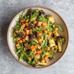 High-Protein broccoli salad with tofu, chickpeas, arugula, dried cranberries, and hemp hearts in a bowl.