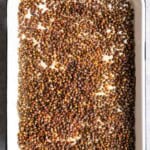 Roasted lentils on a white baking sheet.