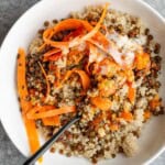 Quinoa, pickled carrots, roasted lentils, and yogurt sauce with tomato chutney in a white bowl.