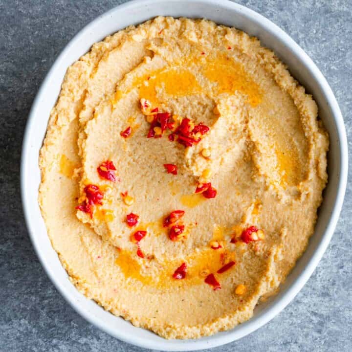 Artichoke hummus with Calabrian chili peppers in a white bowl.