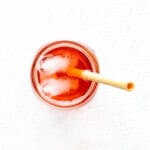 Cranberry water with ice in a mason glass with a bamboo straw.