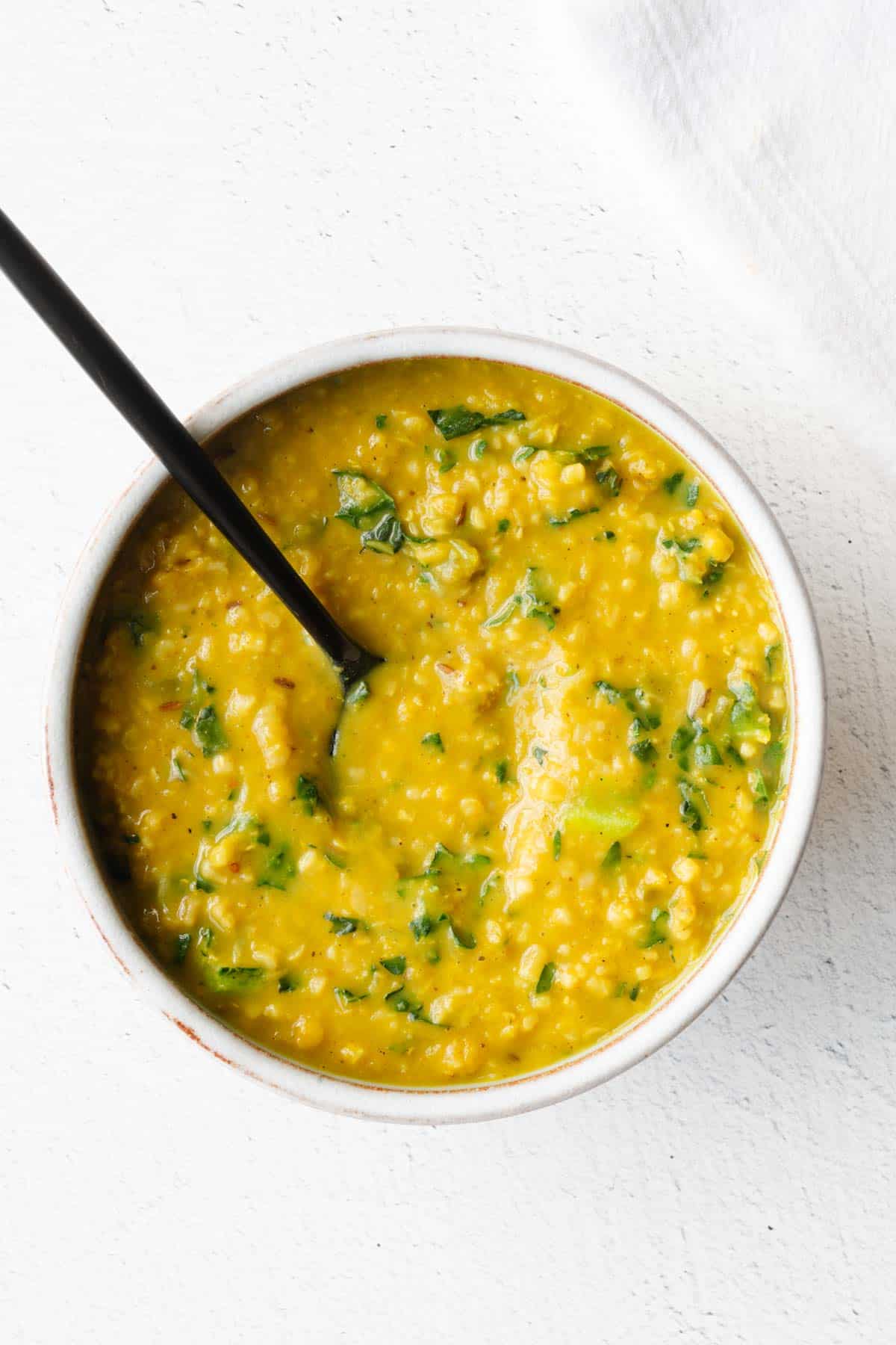 High-protein savory oatmeal with turmeric in a bowl with a black spoon.