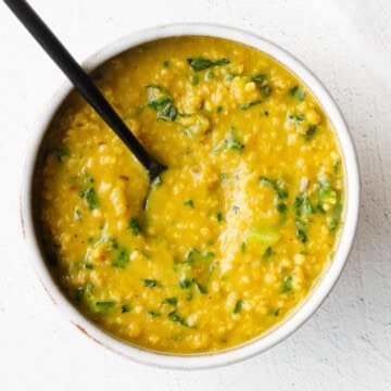 Savory lentil oats with turmeric in a bowl with a black spoon.
