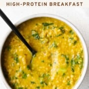 Savory lentil oats with turmeric in a bowl with a black spoon.