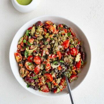 Dense bean salad in a white bowl with green dressing.