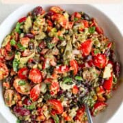 Dense bean salad with kidney beans, lentils, black beans, tomatoes, artichoke hearts, capers, and dressing.