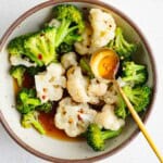 Cruciferous veggie starter recipe with steamed broccoli and cauliflower in a bowl with vinegar dressing in a bowl.
