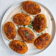 Tofu vegan kebabs on hummus on a white plate.