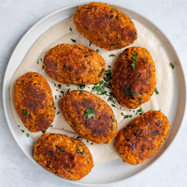 Tofu vegan kebabs on hummus on a white plate.