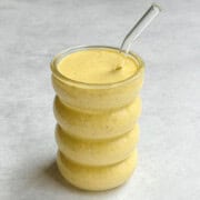 Healthy anti-inflammatory mango lassi in a glass with a straw.