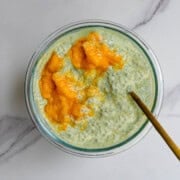 Mango chia pudding with matcha in a glass jar with a gold spoon.