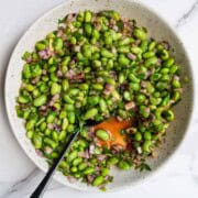 High-protein edamame cucumber salad in a white bowl with a spoon.