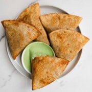 Greek Yogurt Sauce in a white bowl served with samosas.