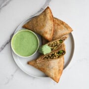 Samosa wraps made form tortillas with a high-protein filling on a white plate, with a green herb yogurt sauce.