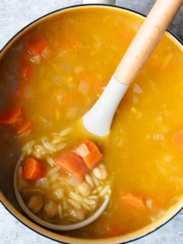 Lemon orzo soup in a white saucepan.