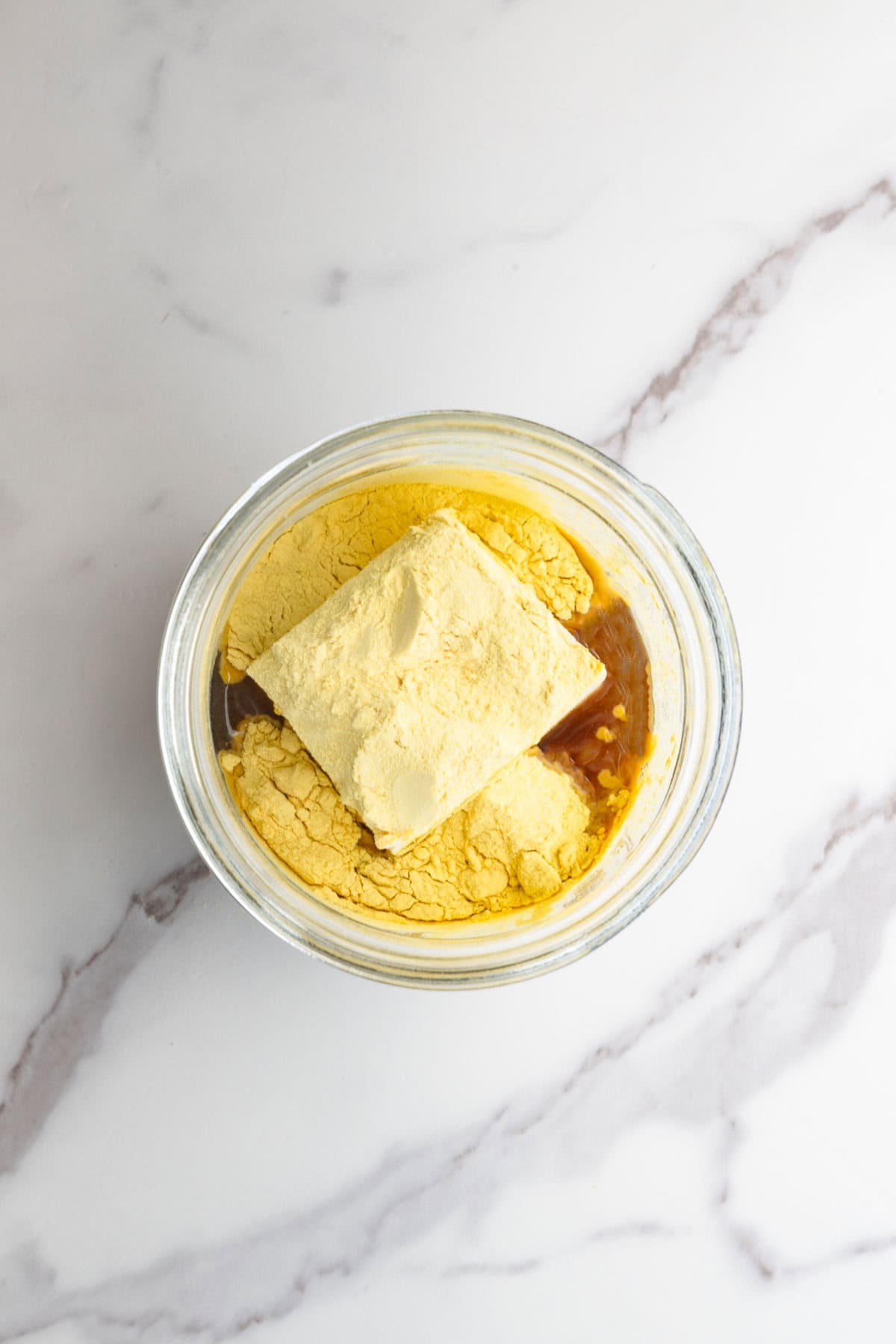 Tofu, nutritional yeast, miso, and broth in a glass jar.