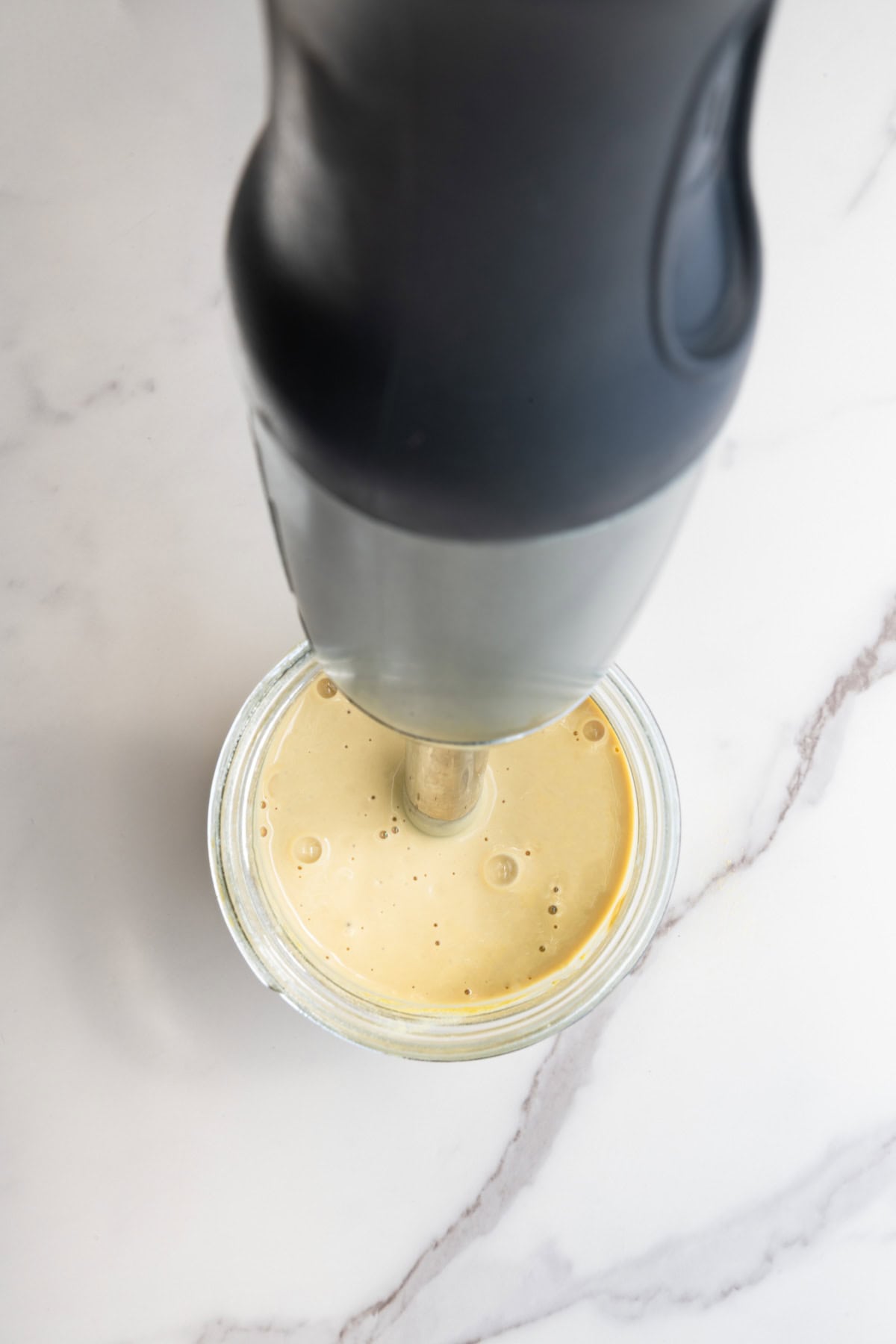 Yellow sauce in a jar with an immersion blender.