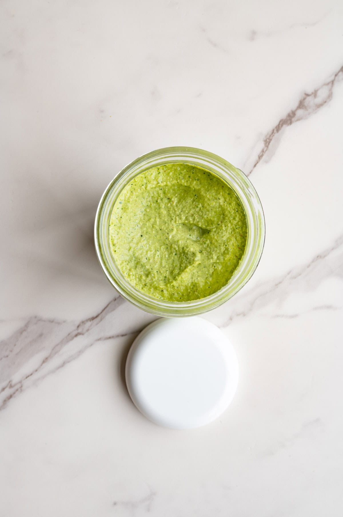 Greek Green Goddess Dip in a glass storage container.