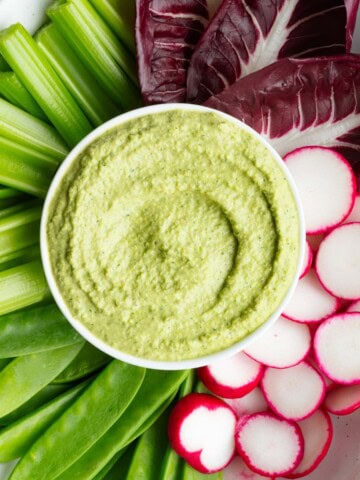 Greek Green Goddess Dip on a white platter with crudités.