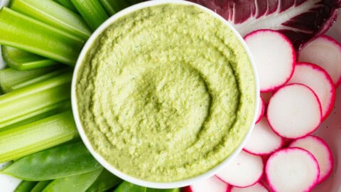 Greek Green Goddess Dip on a white platter with crudités.