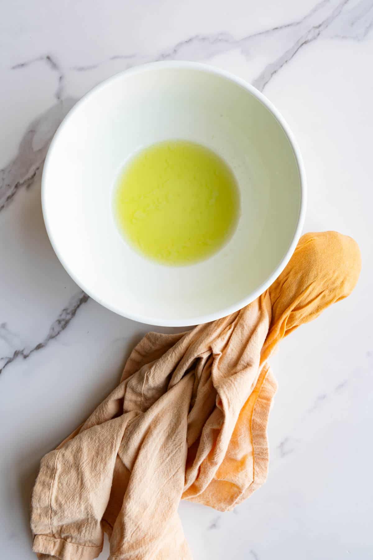Squeezed zucchini liquid in a bowl with shredded zucchini in a napkin.
