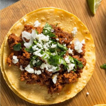 Tofu taco meat on tacos with vegan feta and chopped fresh herbs.