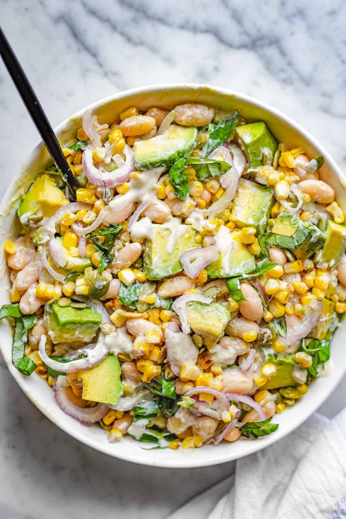 Creamy lemon pepper dressing with High-Protein Bean & Corn Salad: shallot, avocado, corn, basil, jalapeño, pepitas, and white beans.