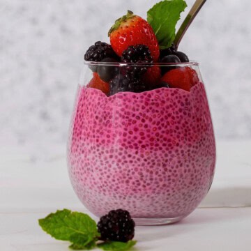 High-Protein berry chia pudding with yogurt in a glass topped with fruit.