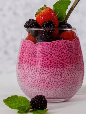 High-Protein berry chia pudding with yogurt in a glass topped with fruit.