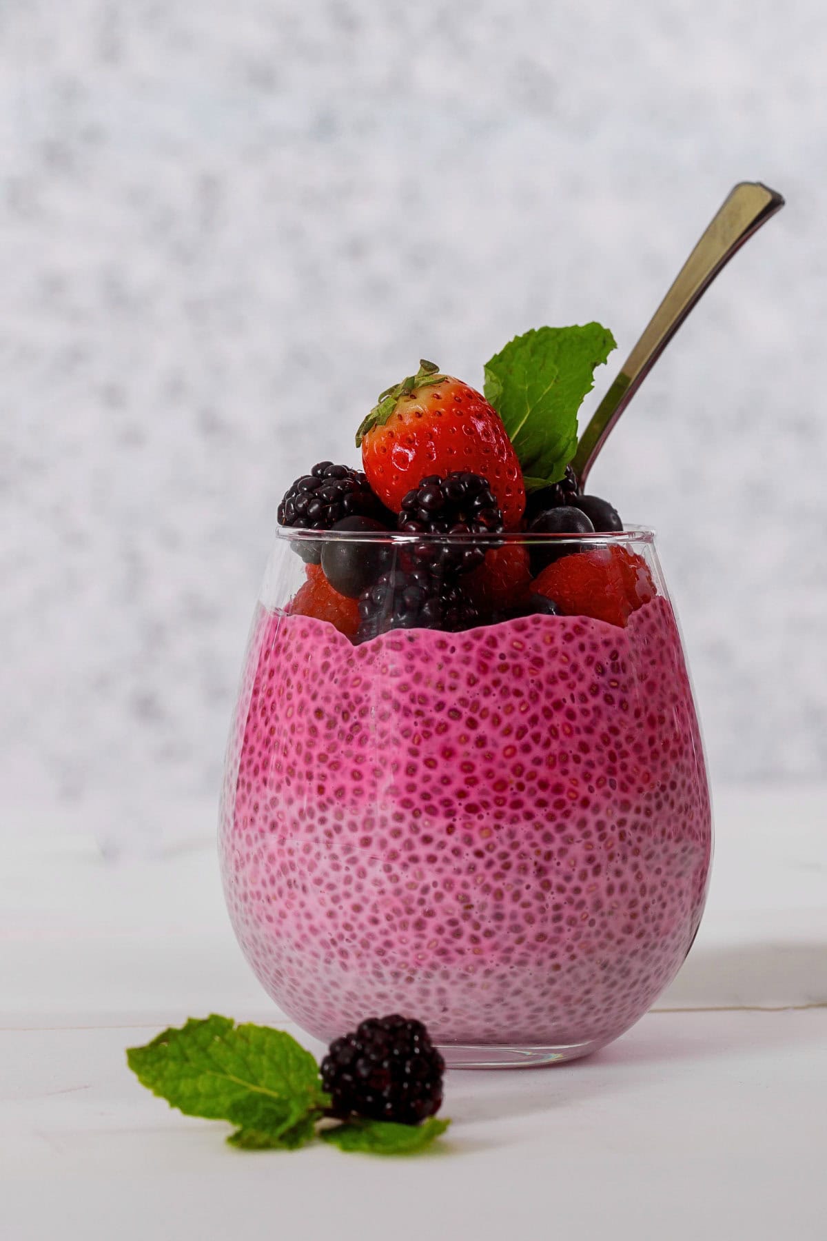 High-Protein berry chia pudding with yogurt in a glass topped with fruit.