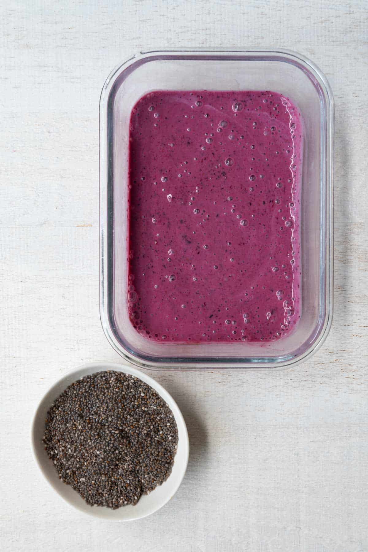 Blended yogurt, berries, forzen fruit and date next to soaked chia seeds.