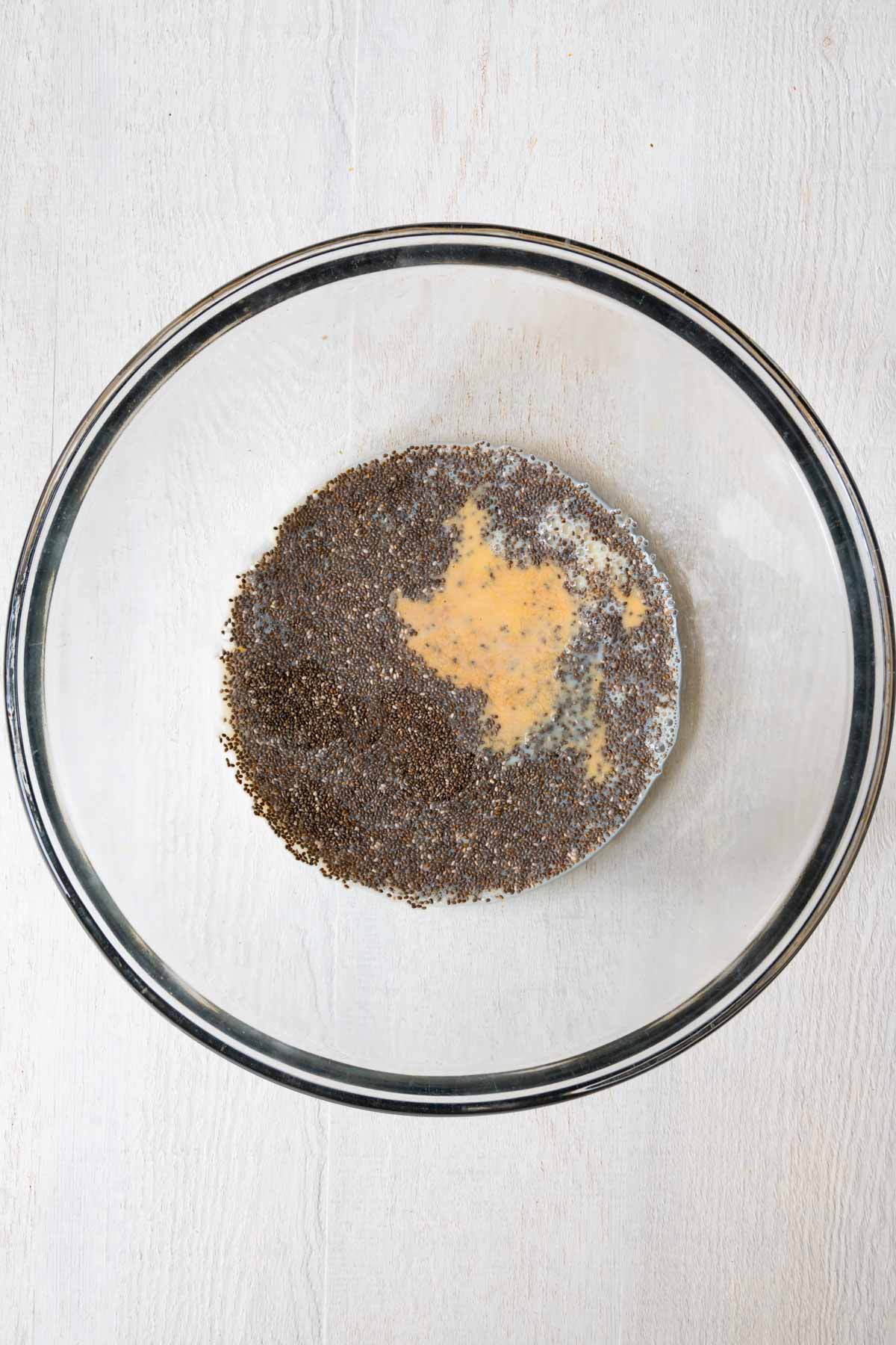 Chia seeds, vanilla, and nondairy milk in a glass bowl.