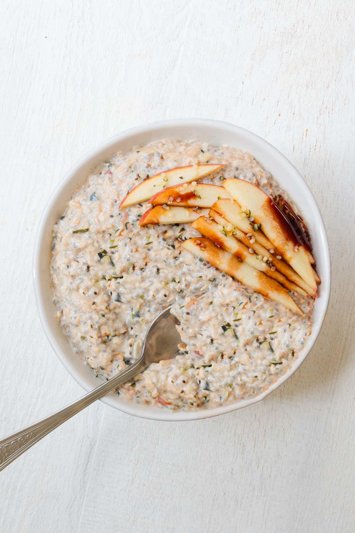 High-protein chia seed oatmeal in a bowl topped with sliced apple and date syrup.