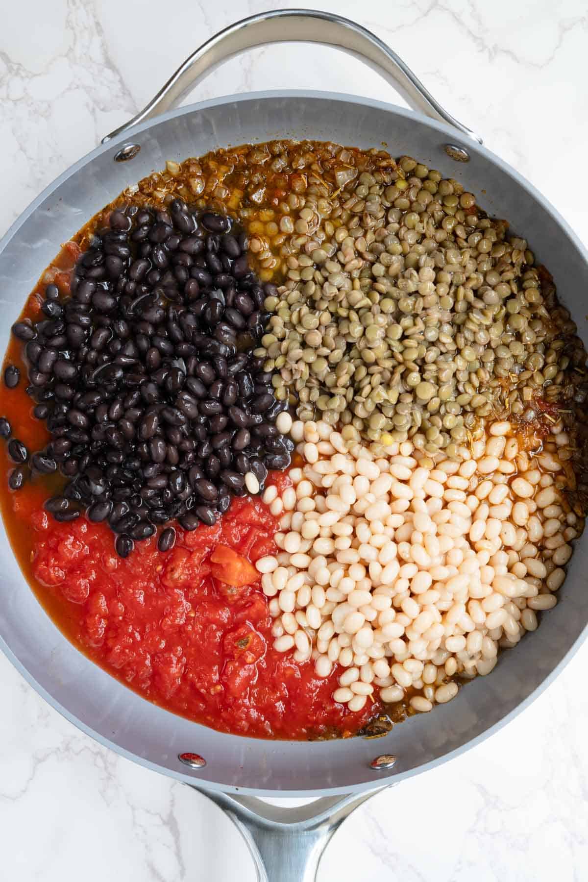 White beans, black beans, lentils, and diced tomatoes in a saucepan.