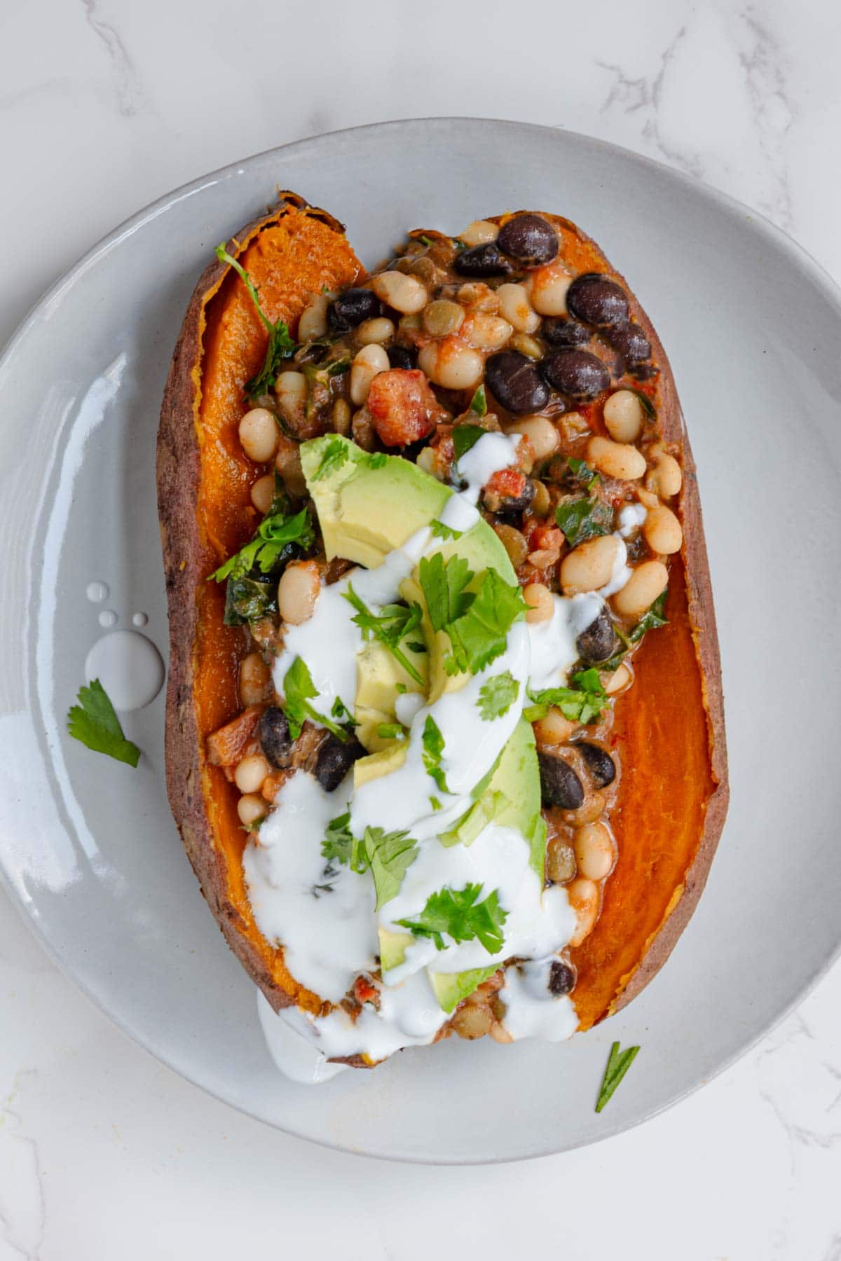 Chili with beans in a sweet potato topped with vegan sour cream , avocado, and cilantro.