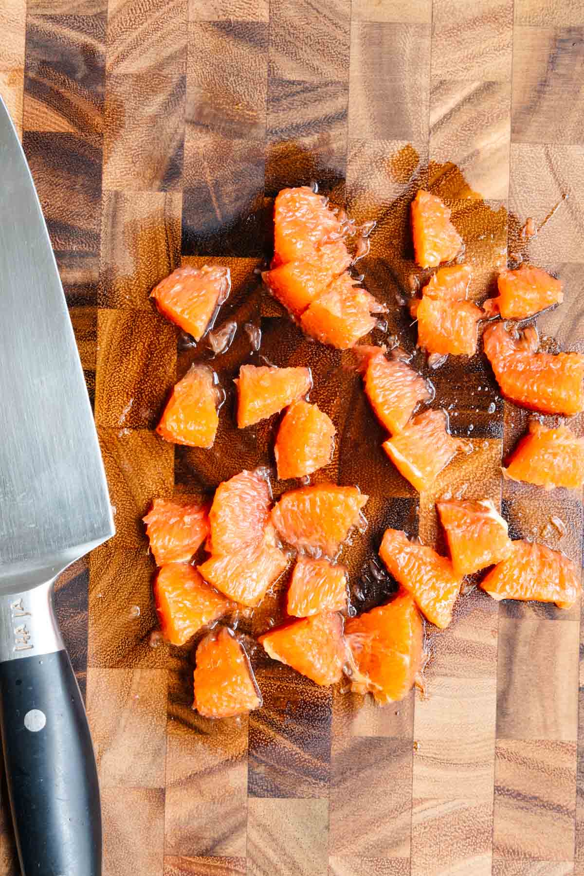 Chopped orange segments on a wooden cutting board.