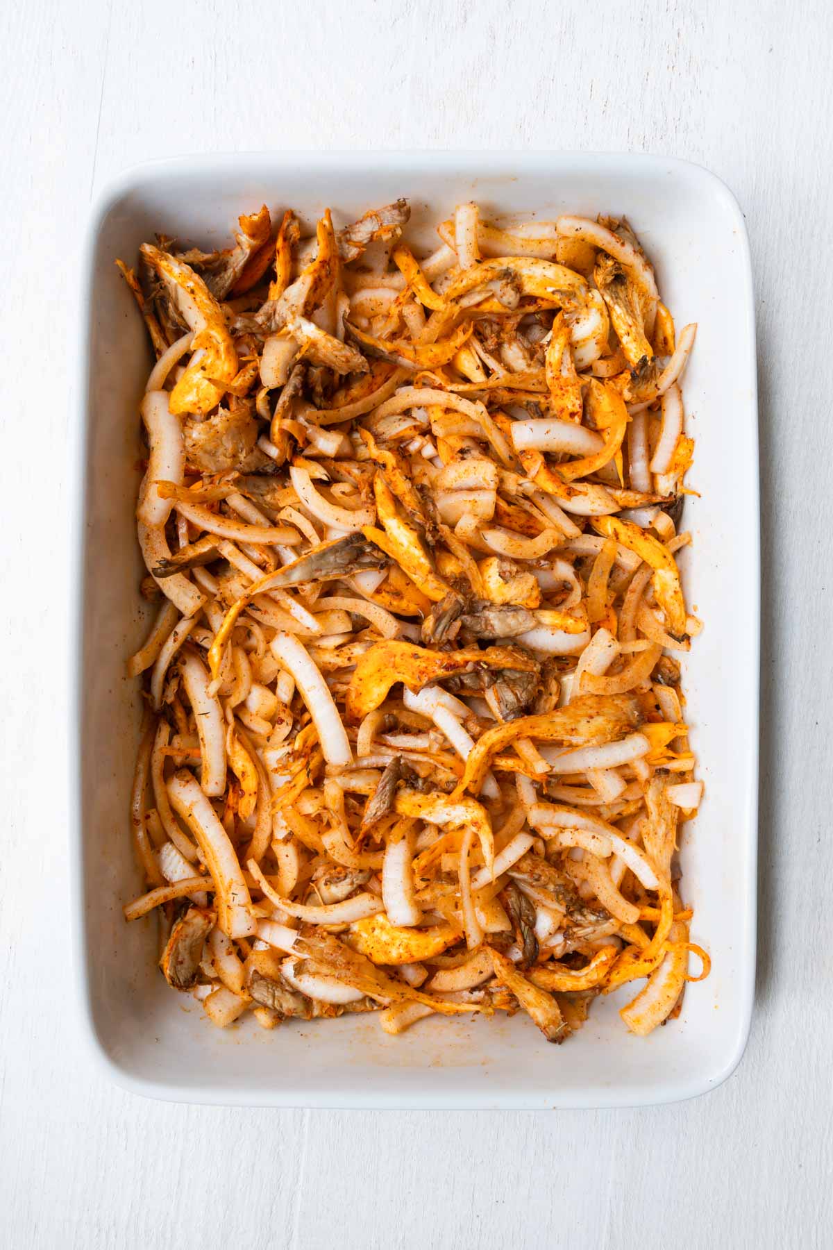Cooked mushrooms and tofu in a white baking dish.