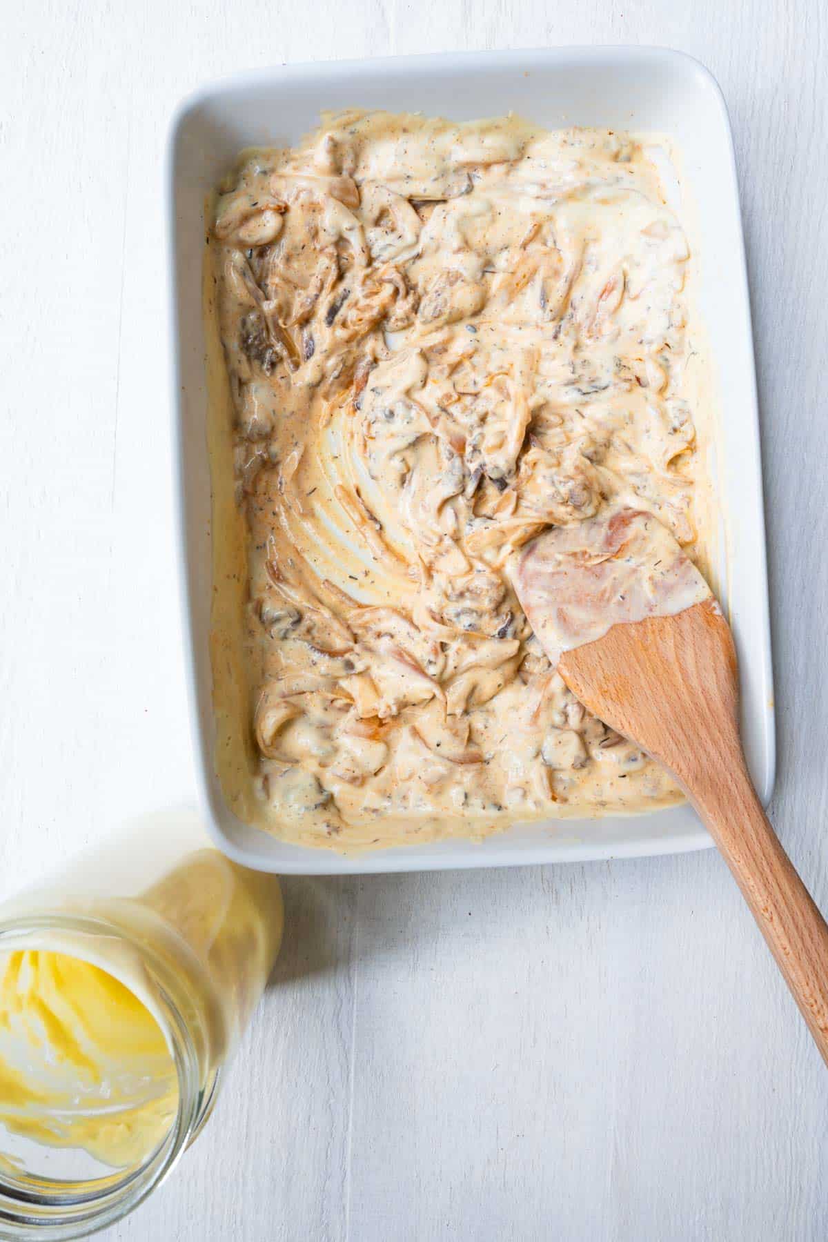 Creamy mushrooms and onion in a white baking dish.