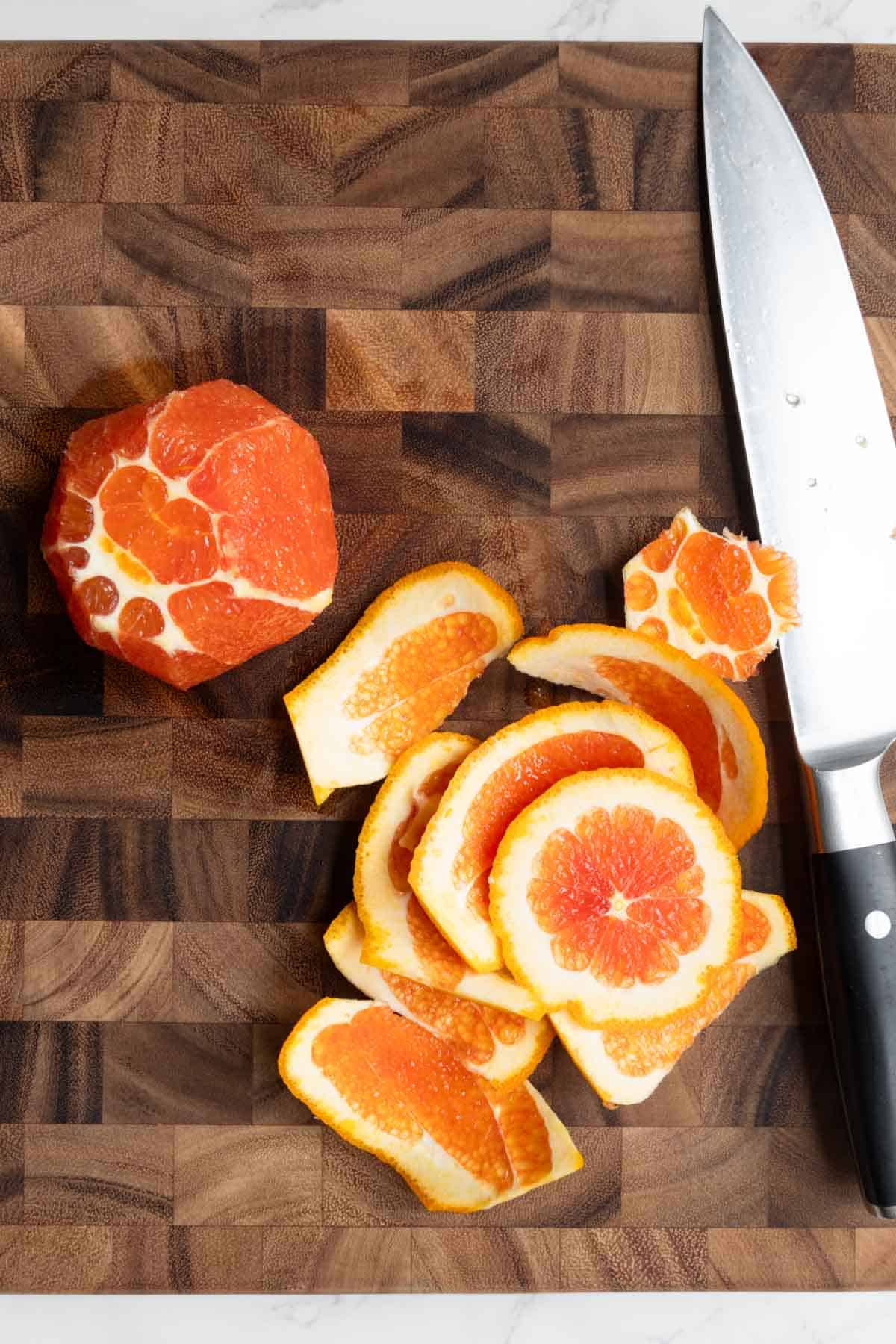 A peeled orange on a cutting board with a knife.