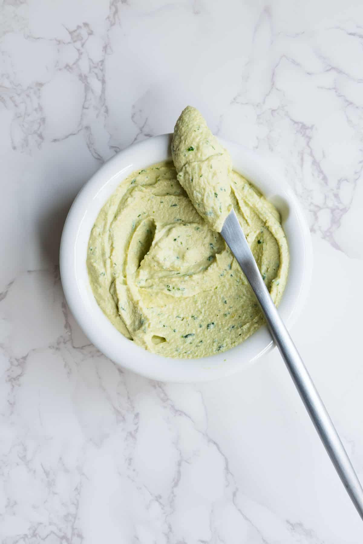 Dairy-free cream cheese in a white bowl with a silver knife.