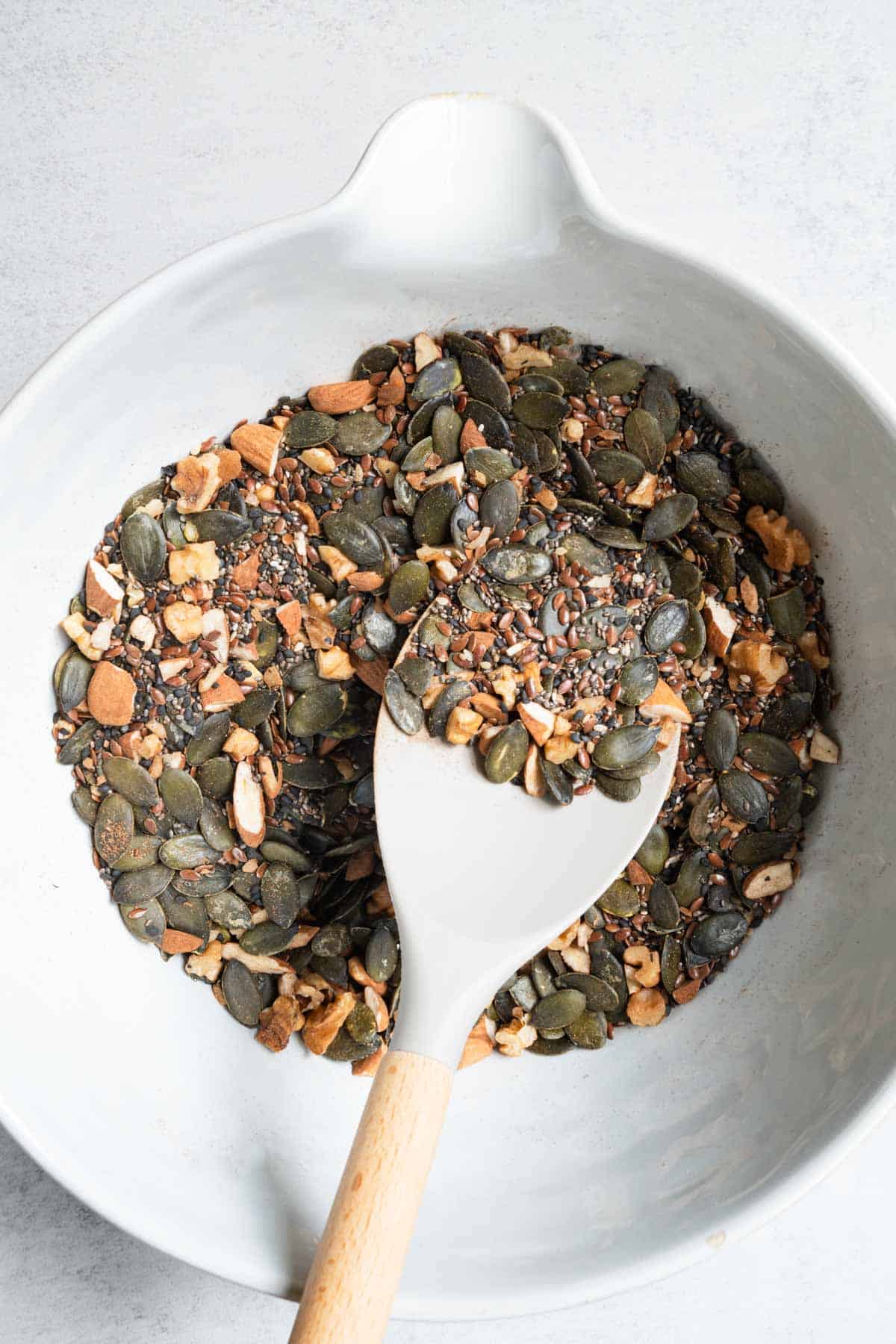 Nuts and seeds for grain-free granola in a large bowl with a spatula.