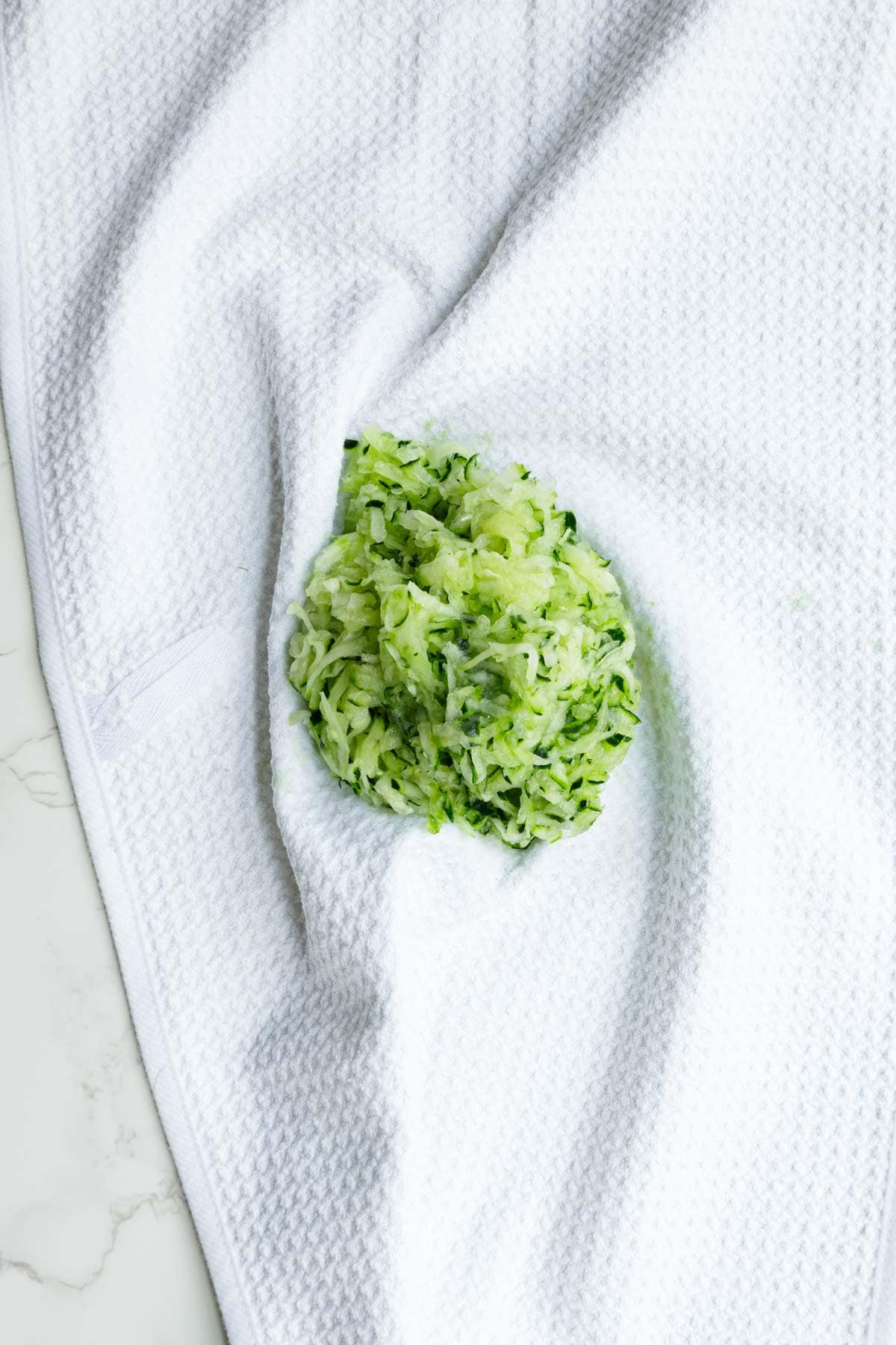 Grated cucumber squeezed in a white kitchen towel.