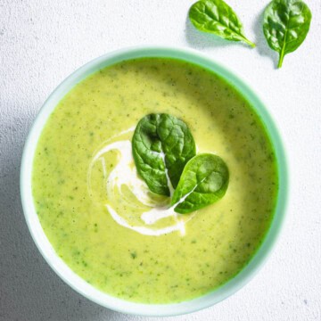 High-protein creamy greens and beans soup in a bowl topped with greens.