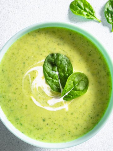 High-protein creamy greens and beans soup in a bowl topped with greens.
