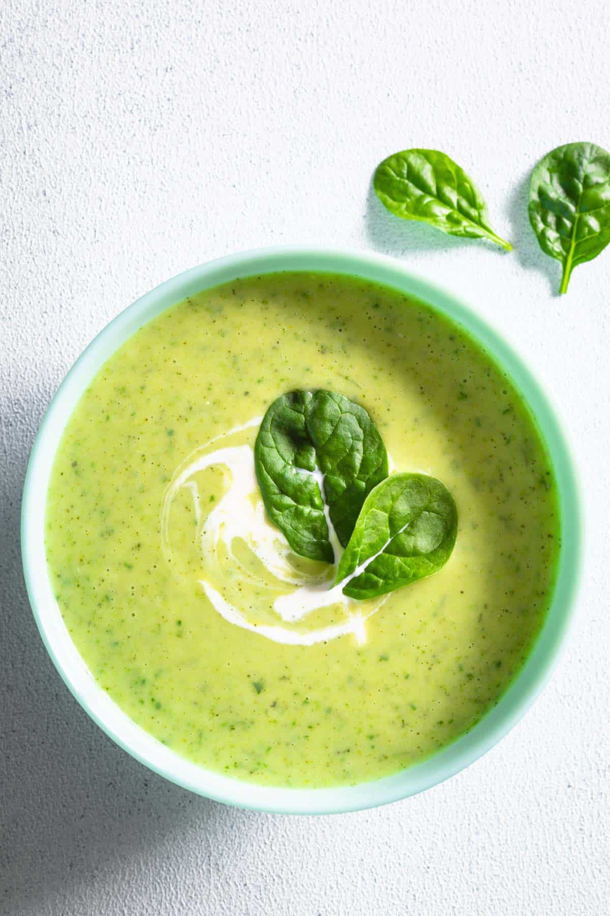 High-protein creamy greens and beans soup in a bowl topped with greens.