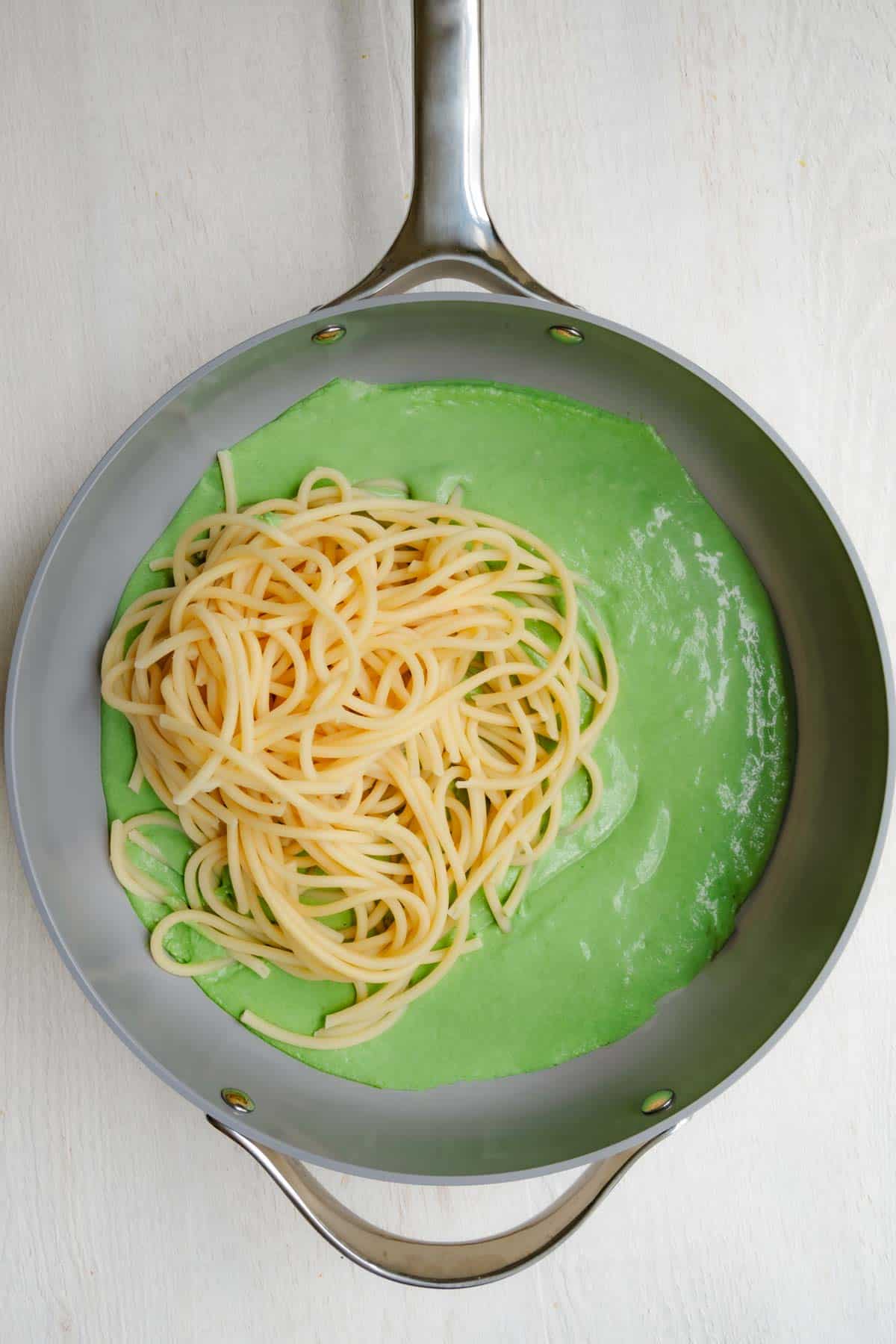 Sauce in a large skillet topped with cooked spaghetti.