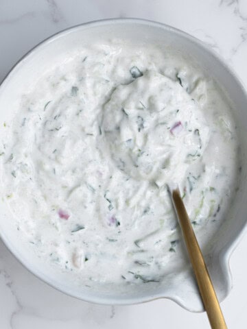 High-protein raita in white bowl with a gold spoon.