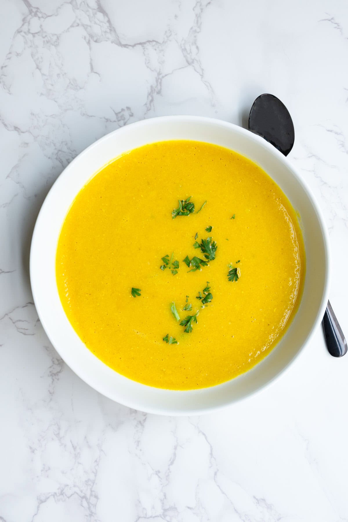 Red lentil carrot soup blended in a white bowl.