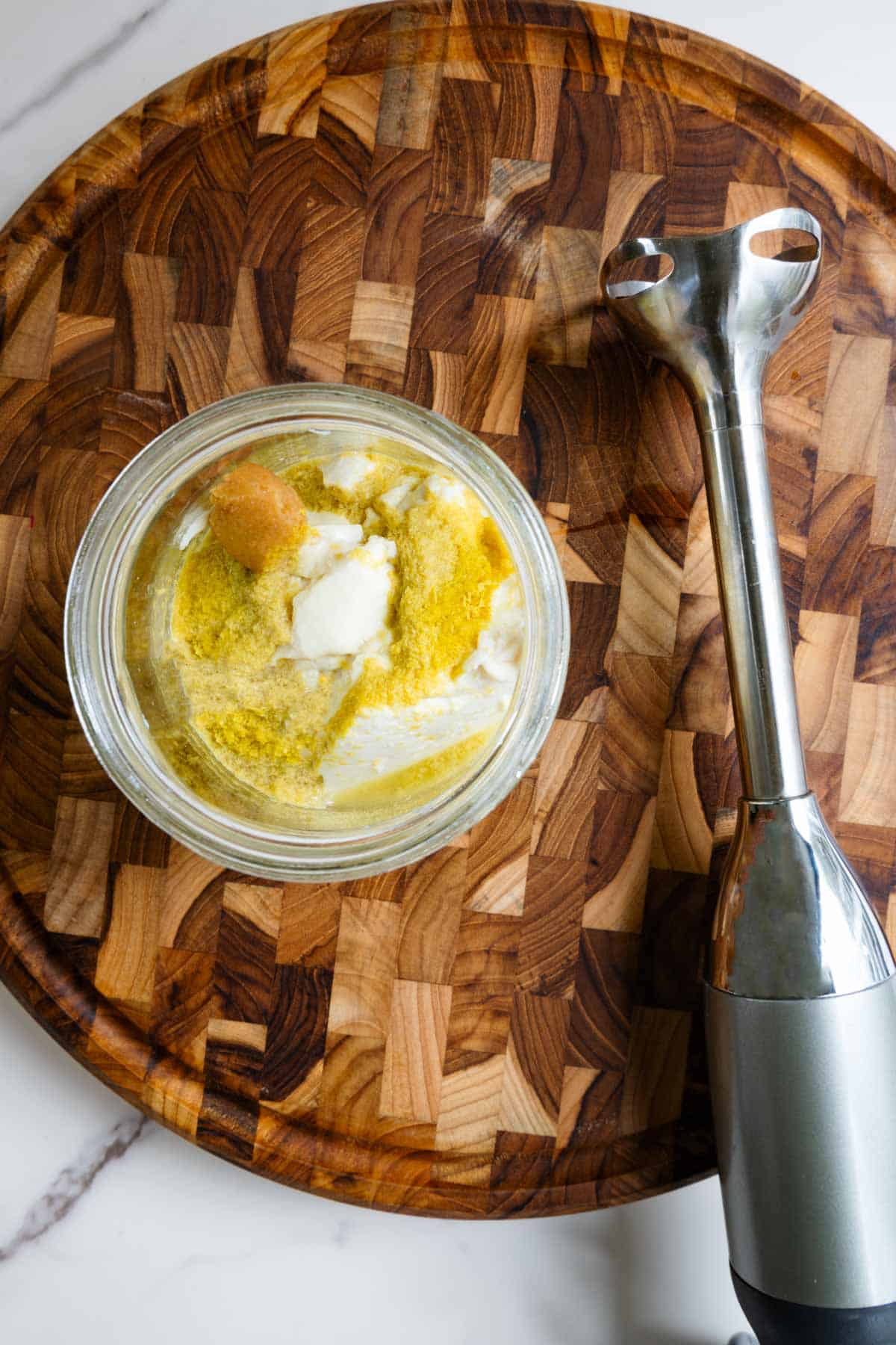 Ingredients for dairy-free cream in a jar with an immersion blender.